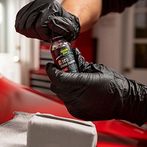 Person applying car glass coating with gloves.